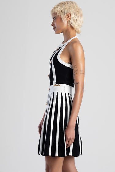 side view of a woman wearing a black and white striped knit dress with gold buttons and white trim