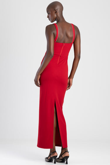 back view of a red maxi dress with wide straps, a center back zipper and a high slit, worn by a model in black heeled sandals