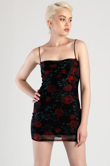 model wearing a black rose print mini dress with spaghetti straps