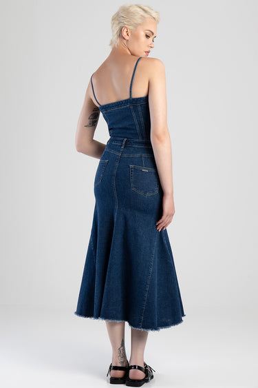 woman in a blue denim midi dress with thin spaghetti straps, fitted bodice, back pockets, and a frayed hem, wearing black