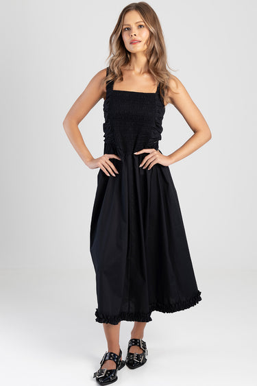 woman wearing a black midi dress with smocked bodice, ruched sides and a frilled hem by Blue Jean Traders