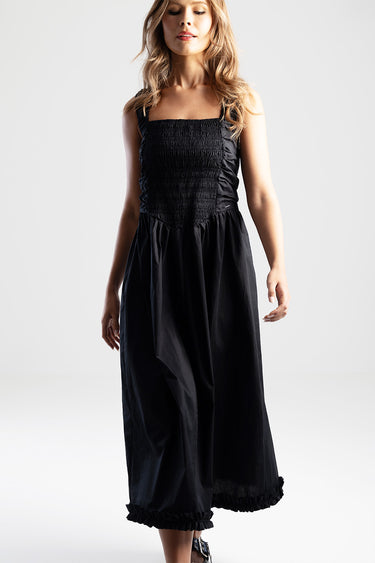 woman wearing a black midi dress with shirred bodice and wide straps, long skirt with a ruffled hem