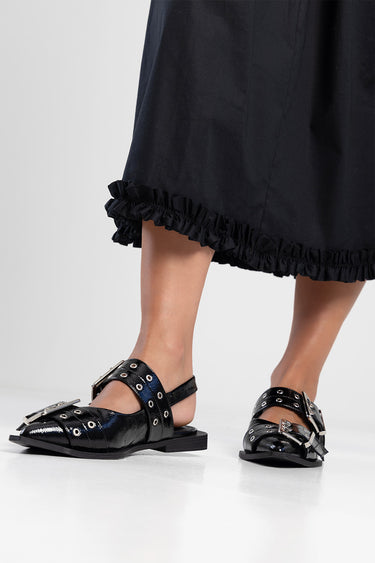 black midi dress hem with a ruffled edge and shiny black sandals with buckles