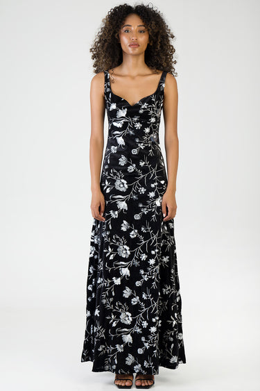 woman wearing a black sleeveless maxi dress with white floral print full length