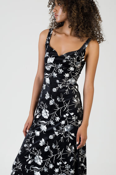 woman wearing a black velvet maxi dress with silver floral embroidery and thin shoulder straps