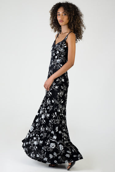 woman in a black maxi dress with silver floral embroidery and thin straps, side profile