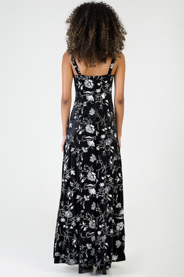 woman wearing a black maxi dress with silver floral embroidery, back view, thin straps, full length