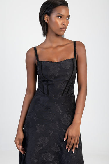 woman in a black floral dress with thin straps and a fitted bodice