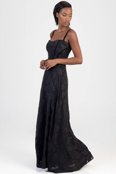 woman wearing a black lace maxi dress with spaghetti straps, floral pattern, fitted bodice and floor-length skirt