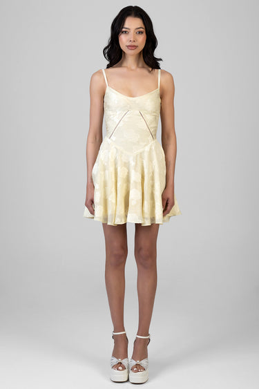 woman wearing a pale yellow lace mini dress with thin straps and a flared skirt, paired with white platform sandals