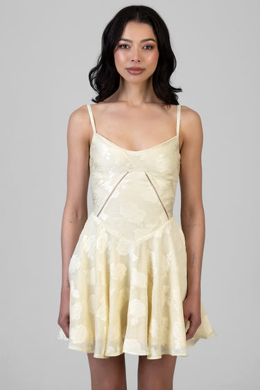 woman wearing a pale yellow floral mini dress with thin straps, fitted bodice and flared skirt