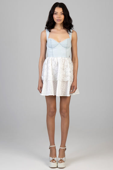 woman in a light blue denim top with a sweetheart neckline and wide straps, and a white eyelet lace skirt with platform