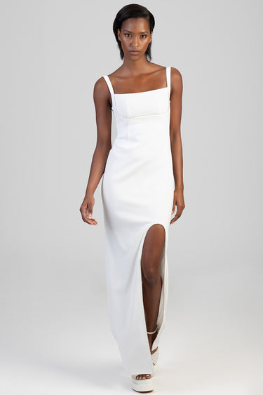 woman wearing a white sleeveless maxi dress with thin straps, beaded trim at the neckline, and a high side slit