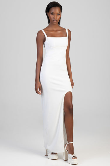 woman wearing a white maxi dress with a square neckline and thick straps side slit and white platform sandals