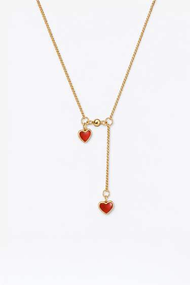 gold tone necklace with red enamel heart charms, featuring a short station and a dangling heart pendant