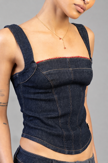 woman in a denim strap top with red trim wearing a gold heart pendant lariat necklace