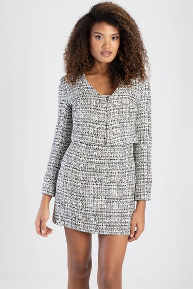 woman modelling a black and white tweed cropped jacket with a matching mini skirt