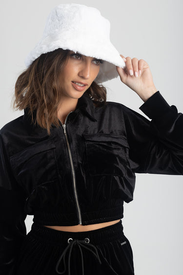 woman wearing a white fluffy bucket hat and a black velour zip jacket
