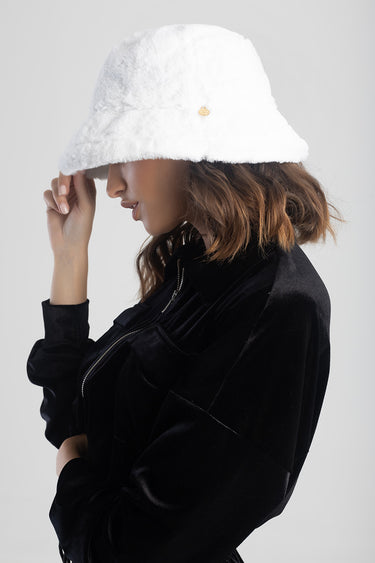 woman in a white fuzzy bucket hat and black velvet jacket, side profile.