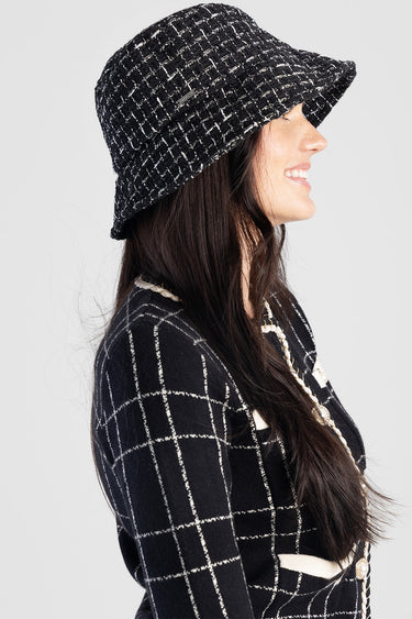 woman wearing a black and white tweed bucket hat with a woven grid pattern.
