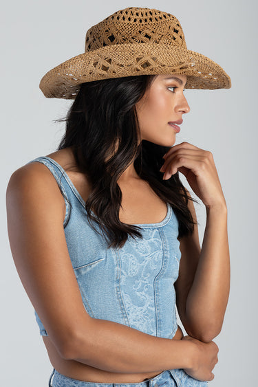 woman in a woven straw cowboy hat and light blue denim top, side profile