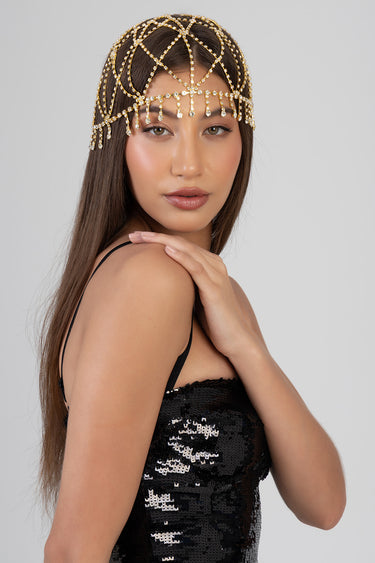 woman wearing a gold crystal headband with dangling beads over the forehead, in a black sequined dress.