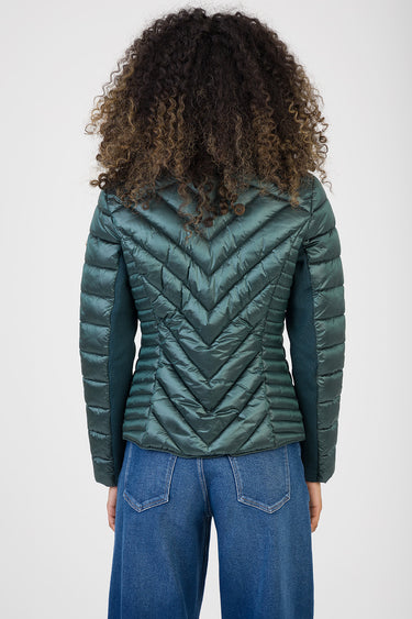 woman from behind in a teal chevron quilted puffer jacket with hood, paired with blue jeans