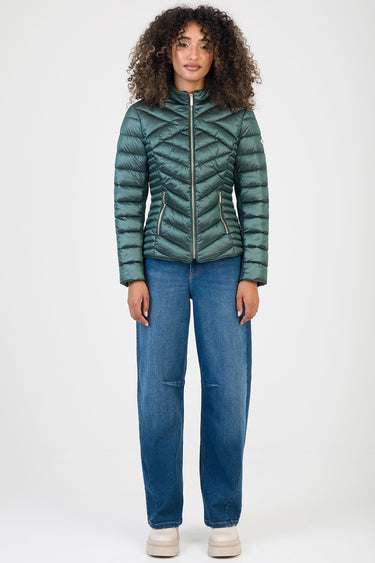 woman wearing teal quilted puffer jacket with diagonal stitching and gold zippers, standing in blue jeans