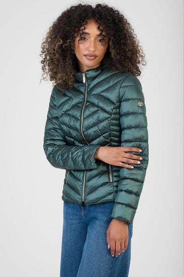 woman with curly hair wearing teal quilted puffer jacket with front zipper and zip pockets