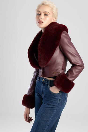 woman wearing burgundy leather jacket with an oversized faux fur collar and matching cuffs, paired with blue jeans