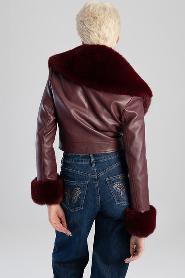 back view of burgundy faux fur jacket with oversized collar and cuffs, leather like material, paired with dark jeans