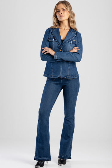 woman in blue denim blazer with gold buttons and matching flared jeans standing with arms crossed