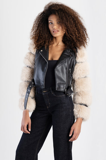 woman wearing a black leather biker jacket with beige fur sleeves and a belt, paired with dark jeans