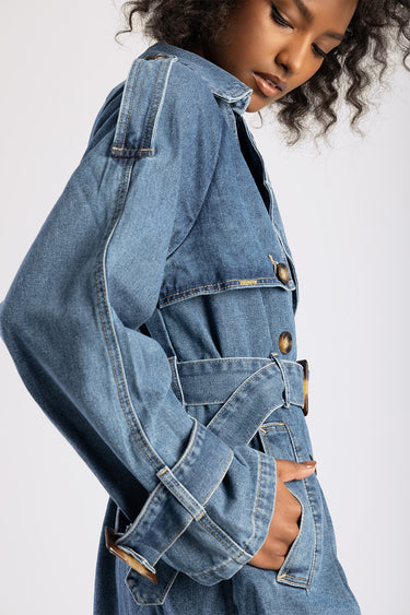 woman wearing a blue denim trench coat with belt, metal buttons and pockets showing