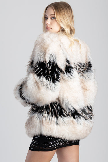 model wearing a thick beige and black faux fur jacket with bold striped pattern.