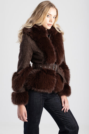 woman wearing a brown faux fur jacket with a wide collar and fur cuffs, belted at the waist with dark denim jeans