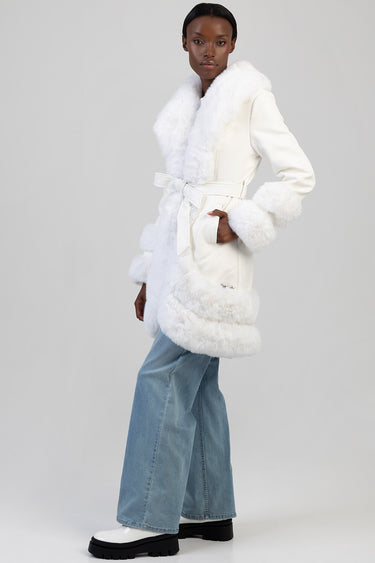 woman in a white faux fur trimmed belted coat with oversized cuffs, paired with light blue wide leg jeans and white chunky
