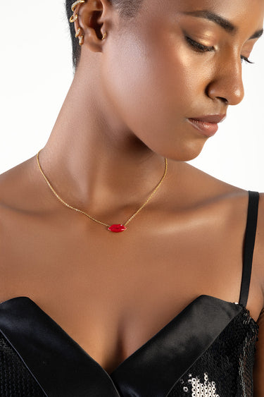 woman wearing a gold lip pendant necklace at the base of the neck; close up of face and shoulders