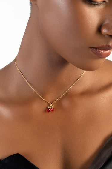 gold chain necklace with red cherry pendant on a woman's neck