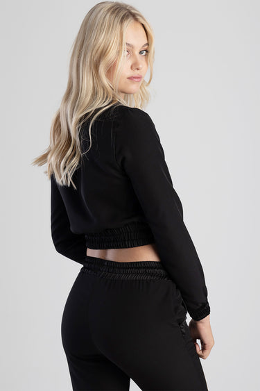 woman in black cropped jacket with smocked waistband, back view