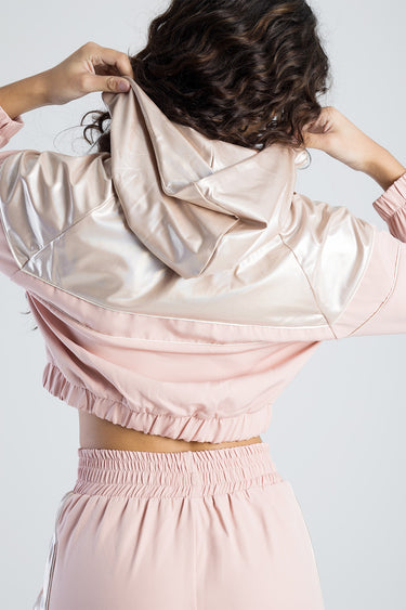 back view of a pale pink cropped tracksuit top with a metallic hood and elastic hem