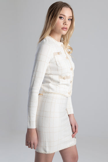 woman wearing cream check knit jacket with gold buttons and braided trim, matching skirt, side view