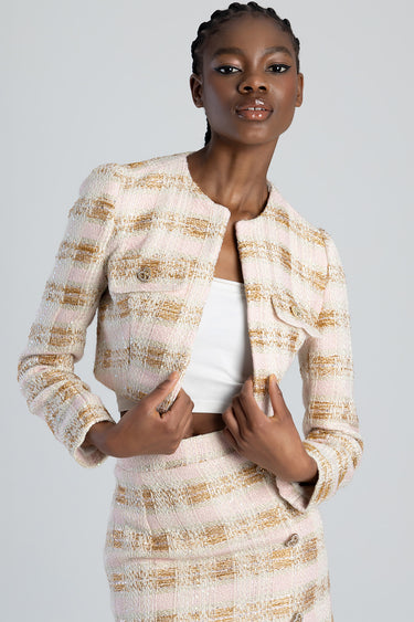 model wearing a pink and beige textured tweed jacket with a matching skirt and white top