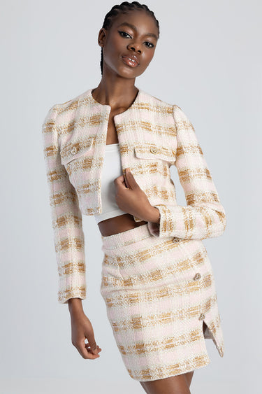 woman wearing a pink beige plaid tweed jacket and matching skirt with a white top