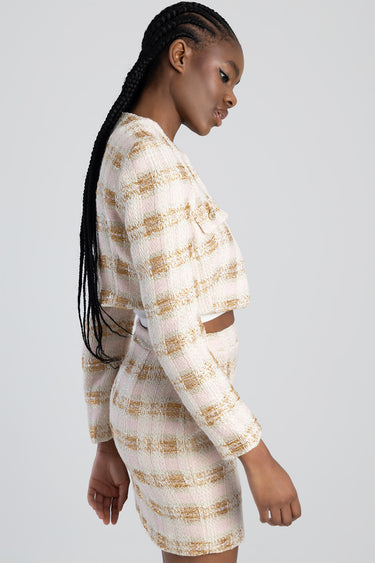 side profile of a woman wearing a pink and gold tweed cropped jacket with a matching mini skirt
