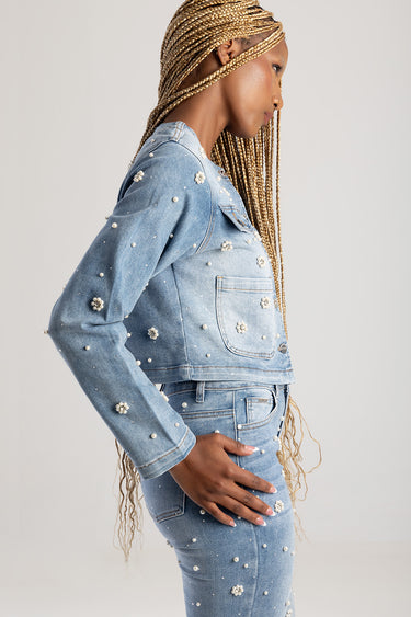 side profile of a woman in a light blue denim jacket adorned with pearls, paired with matching jeans