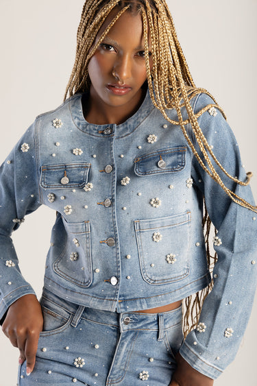 woman wearing light blue denim jacket adorned with pearls and floral bead accents, front pockets and metal buttons