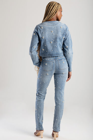 woman wearing light blue denim jacket and jeans with pearl embellishments, back view