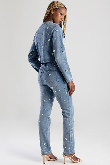 woman wearing light blue denim jacket and jeans covered in pearl embellishments, seen from the back