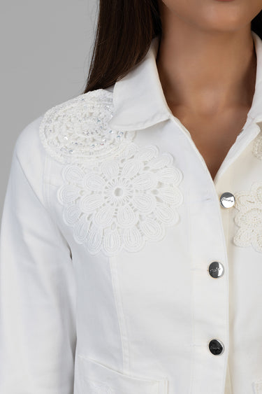white denim jacket with floral lace appliqué on the shoulder and silver buttons